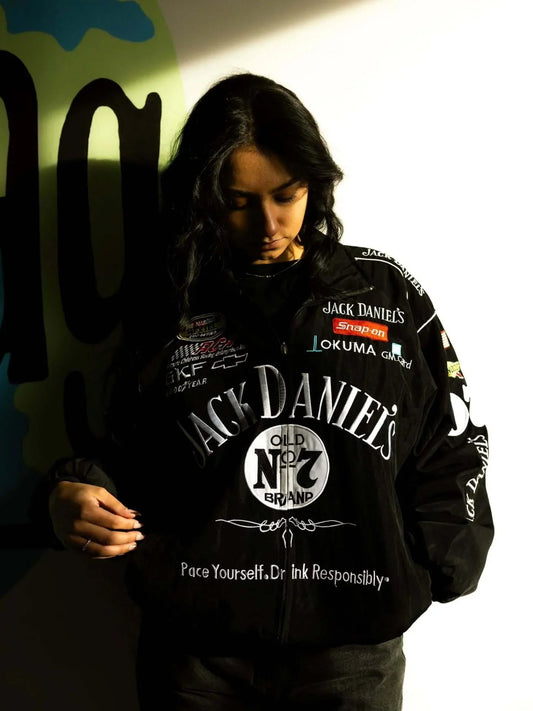 Model wearing Jack Daniels Classic Black Bomber Jacket under moody lighting, showcasing bold front logo and racing-inspired design details.