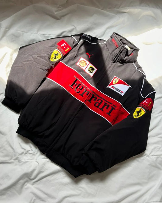 Premium Ferrari Racing Jacket – F1 Streetwear Edition laid flat on a bed, highlighting the red Ferrari logo, sponsor patches, and puffer jacket design.
