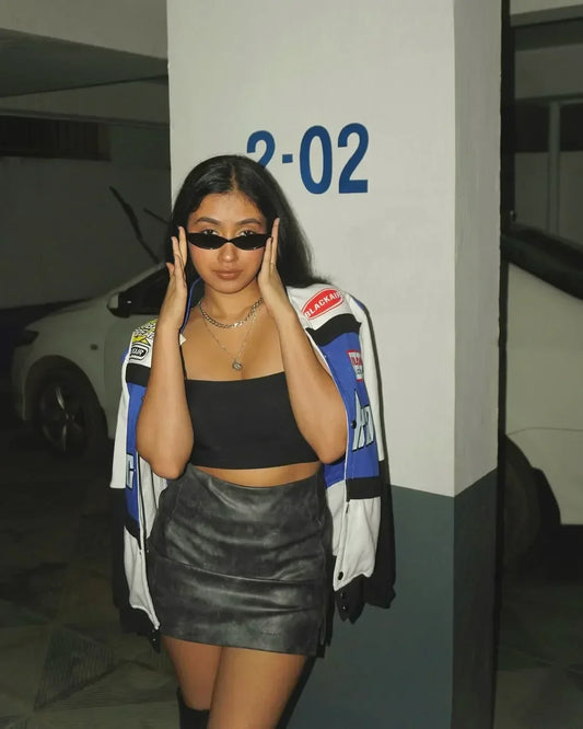 Streetwear classic Blackair Racer Jacket featuring bold racing logos, worn with sunglasses and a black mini skirt for edgy urban fashion.
