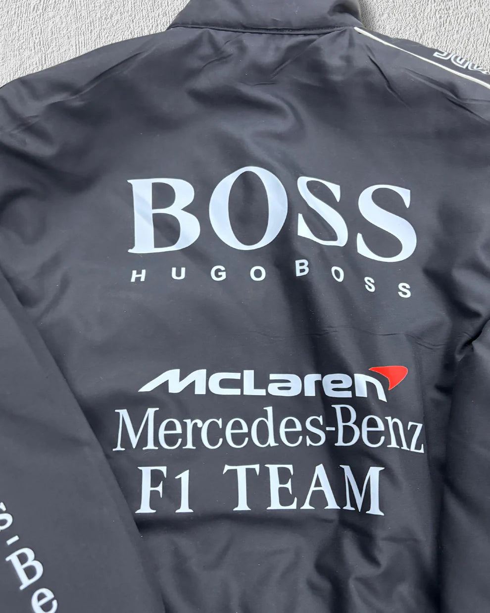 Close-up of McLaren Puffer Jacket back showcasing Hugo Boss and Mercedes-Benz F1 Team logos, emphasizing premium racing-inspired style.