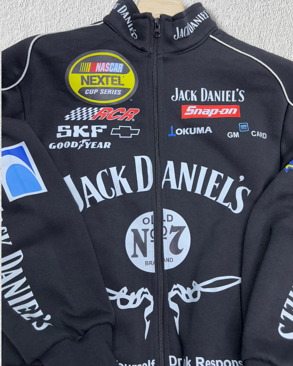 Close-up of Jack Daniel’s Printed Puffer Jacket – Unisex Streetwear showing detailed embroidered logos and racing patches on the chest.