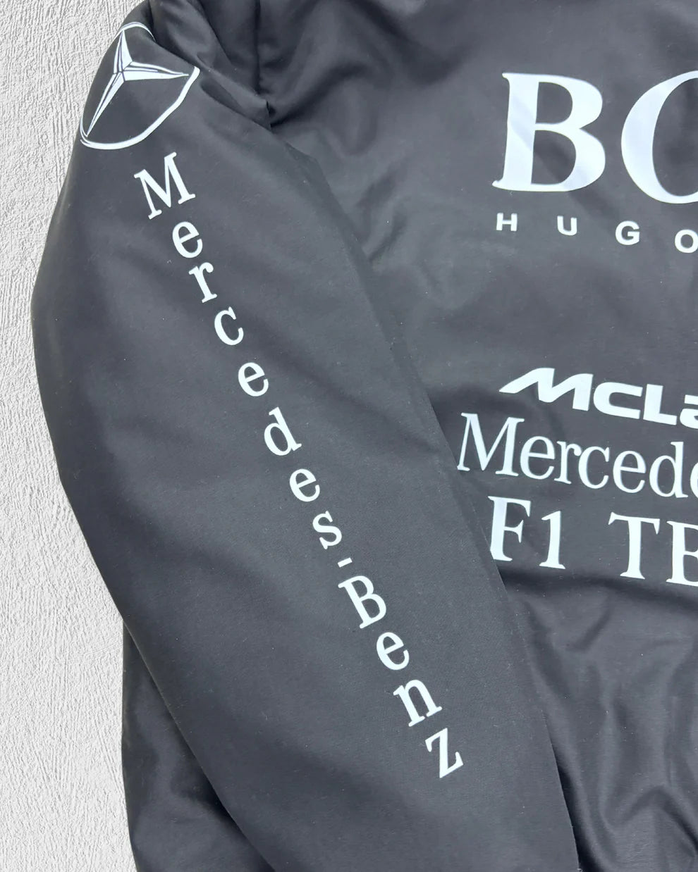 Detailed sleeve view of McLaren Racing Puffer Jacket showing vertical Mercedes-Benz branding, part of durable unisex outerwear collection.