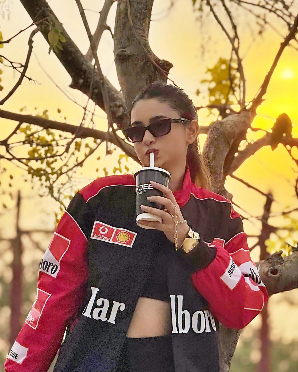 Model wearing Marlboro Racing Puffer Jacket – Motorsport Luxury Edition while sipping a drink, highlighting the jacket's vibrant red and black color scheme.