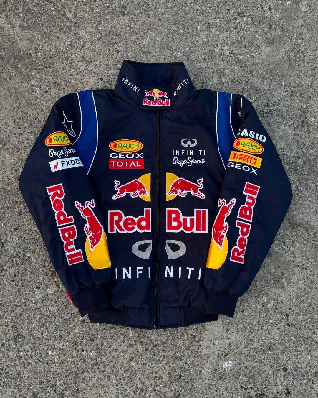 Full front view of Red Bull Racing Jacket in blue with bold Red Bull branding and racing sponsor patches. Lightweight and sleek design.