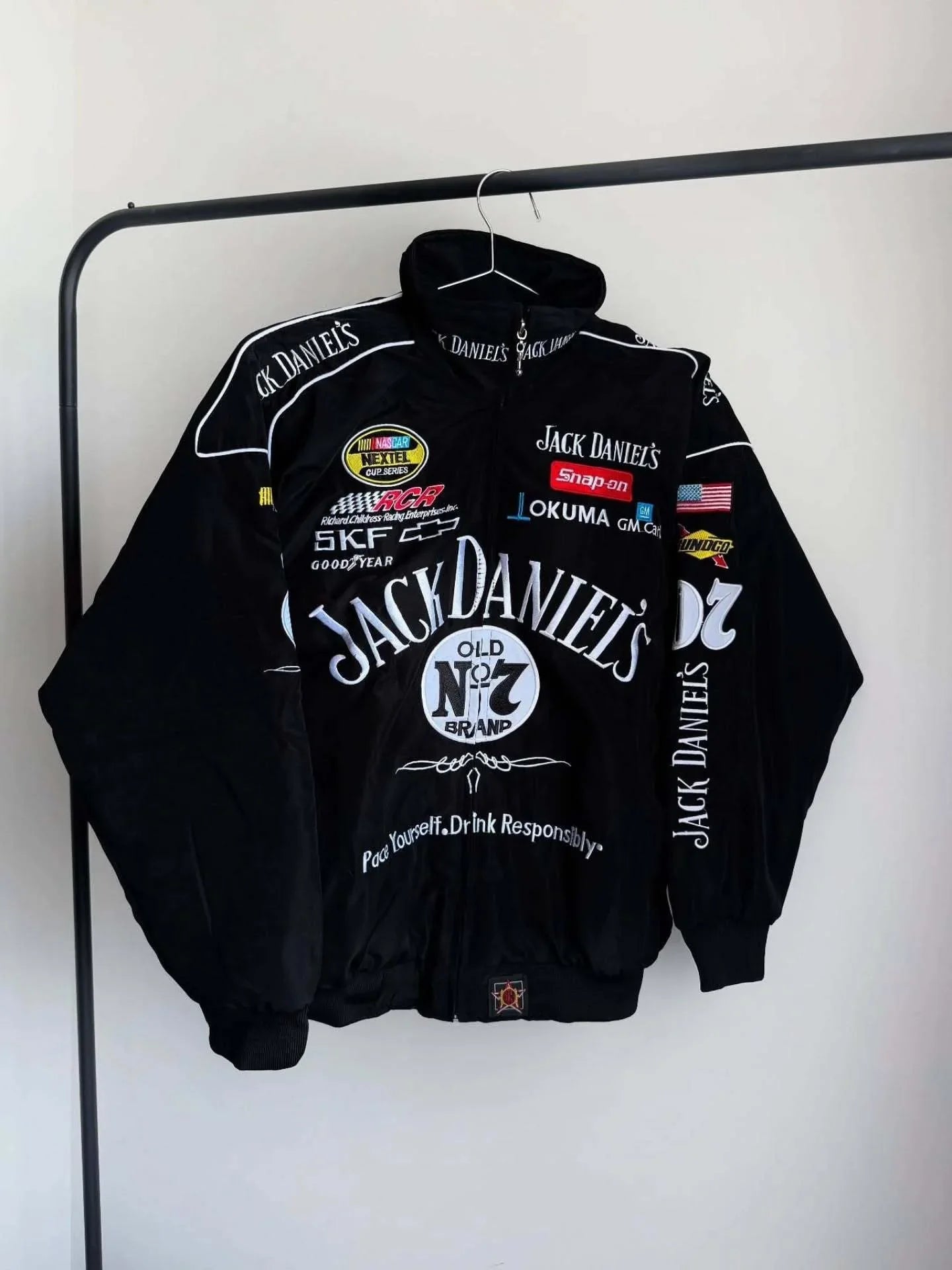 Front view of Jack Daniels Classic Black Bomber Unisex Jacket with racing-style patches and bold Old No. 7 branding. Ideal for casual streetwear.