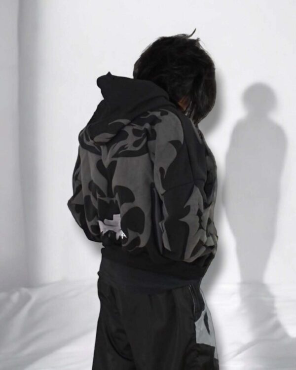 Model wearing oversized tribal shadow depth black hoodie, showcasing urban Indian streetwear with dark abstract patterns.