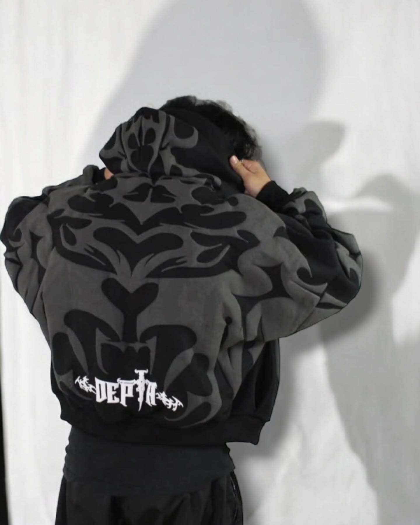 Back view of oversized black hoodie with tribal shadow depth design and 'DEPTA' logo, highlighting Indian streetwear style.