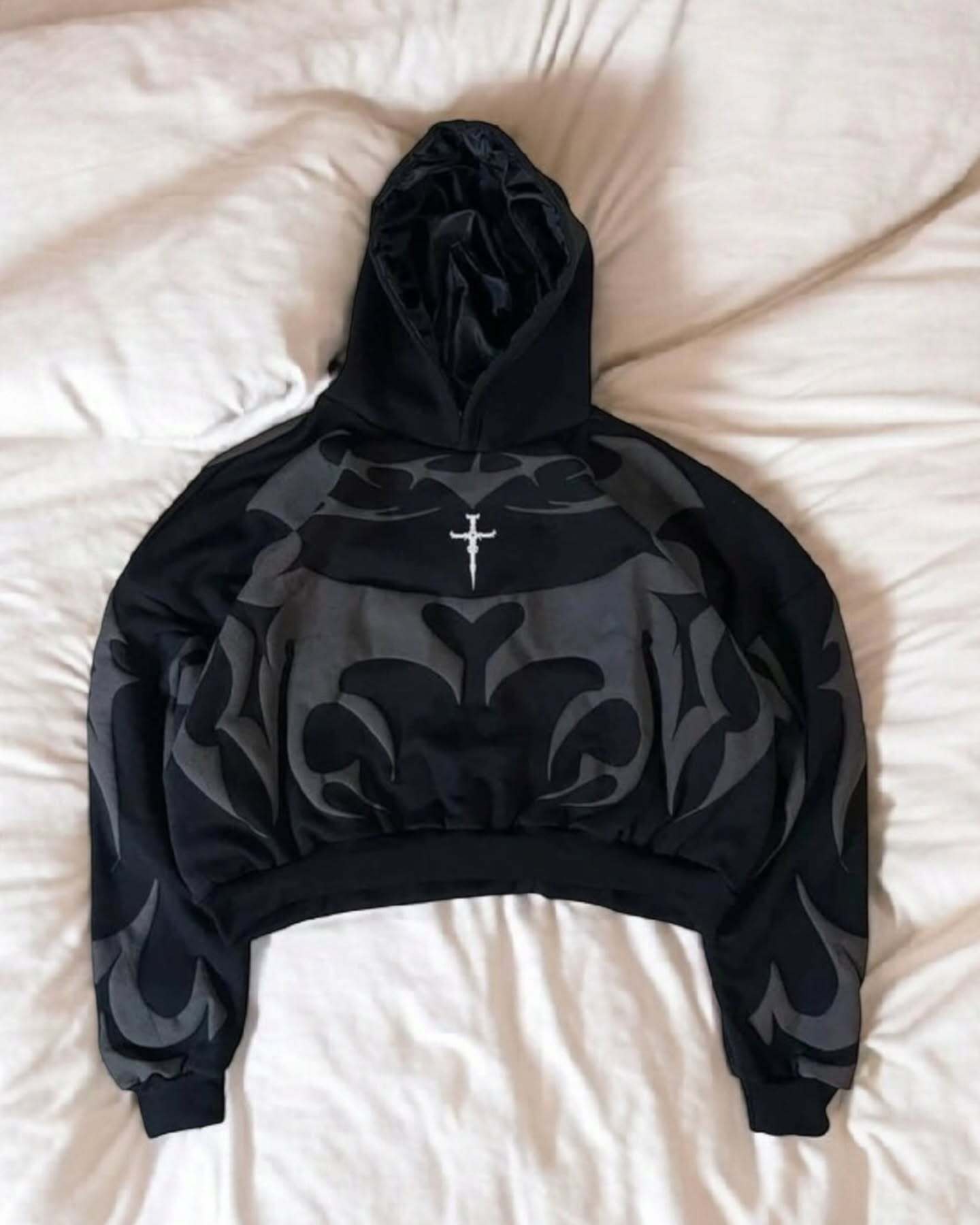 Oversized cream black hoodie with tribal shadow depth design, featuring bold Indian streetwear motifs and front cross emblem.