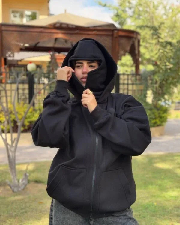 Unisex Ninja Balaclava Hoodie in black fleece with integrated face mask, worn outdoors for a bold streetwear look. Ideal for urban fashion lovers.