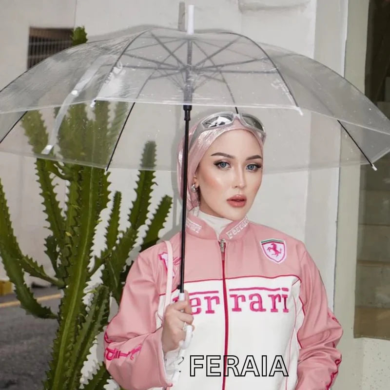 Ferrari Vegan Leather Jacket in pink and white with vintage racing design, worn outdoors under a clear umbrella. Stylish sustainable outerwear.